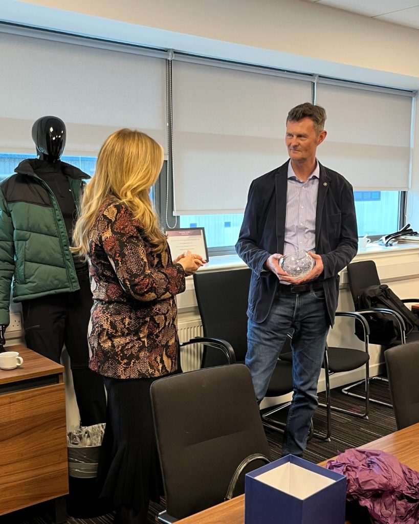 Lord Lieutenant, Lady Susan Haughey (Left) presents Andrew Rough, CEO of ACS (Right), with the King's Award for Enterprise onsite at the ACS Circular Fashion Hub.The Award resembles a glass bowl with the King's Award for Excellence logo on the front, noting that it is the award for the Sustainable Development category.