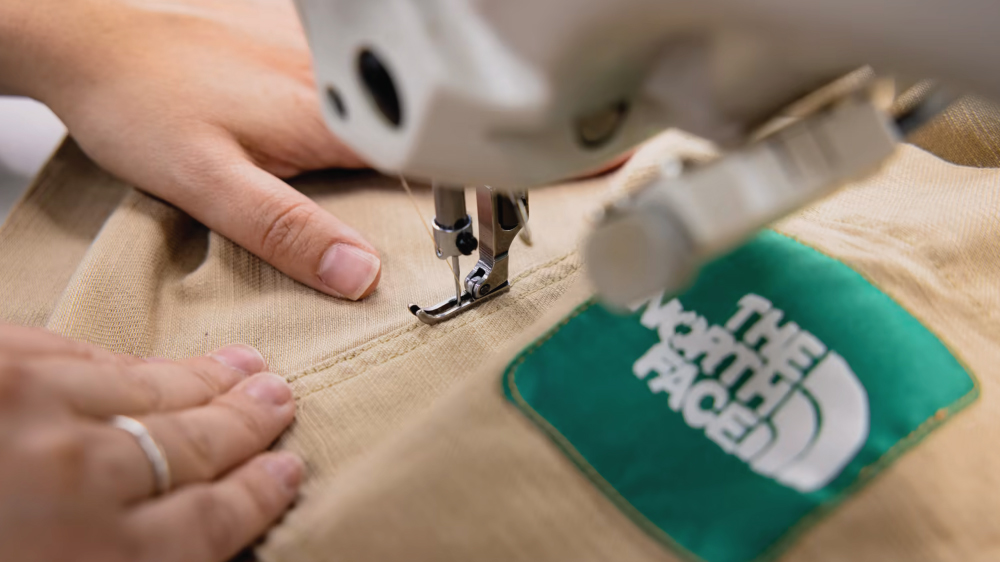 Someone using a sewing machine on a The North Face Renewed garment