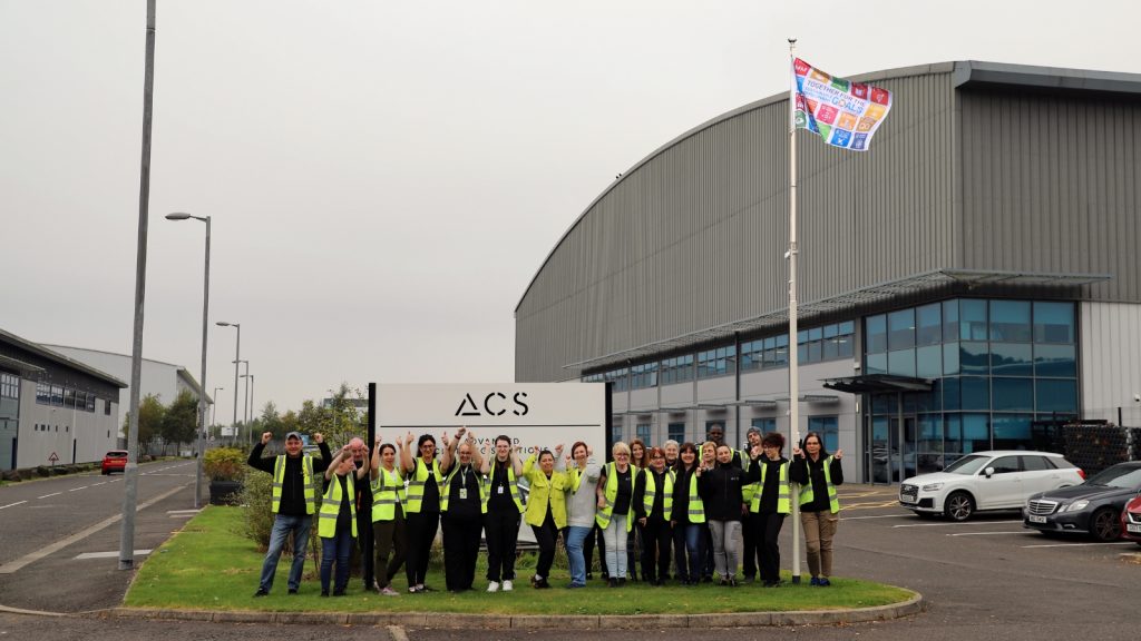 ACS staff stood beside ACS sign in front of the Circular Fashion Operation celebrating.